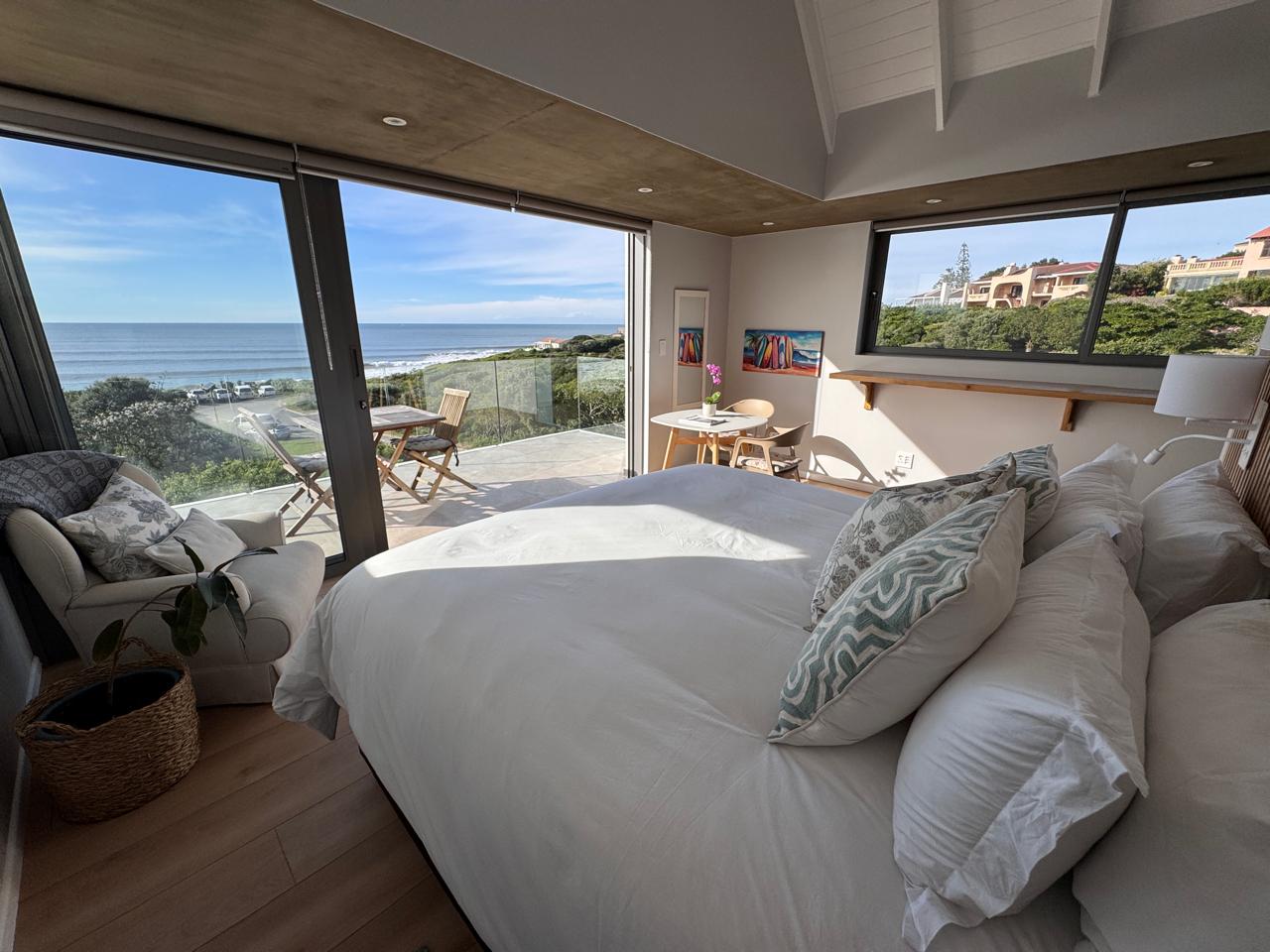 Luxury seafront suite with king bed opening onto an ocean-view terrace